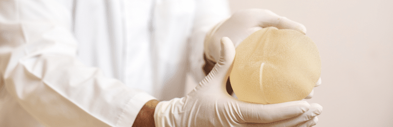 Closeup of breast implant in plastic surgeon hands. Concept of plastic surgery and breast augmentation